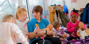 children around lady holding dolly