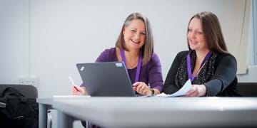 two ladies looking at a laptop