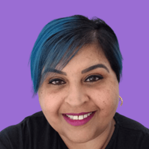 Smiling person with short blue hair against a purple background.