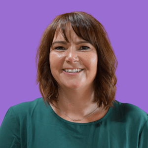 A smiling woman with shoulder-length brown hair and bangs is wearing a green top. She is set against a solid purple background.