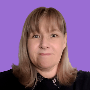 A woman with shoulder-length blonde hair and bangs smiles softly against a solid purple background.