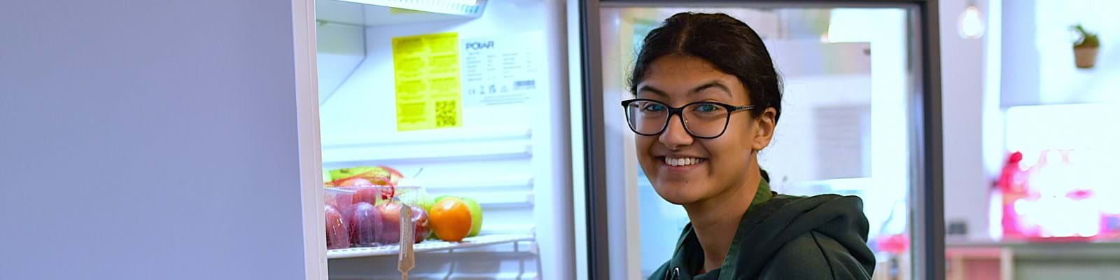 Employee Smiling Next To Open Fridge At Work