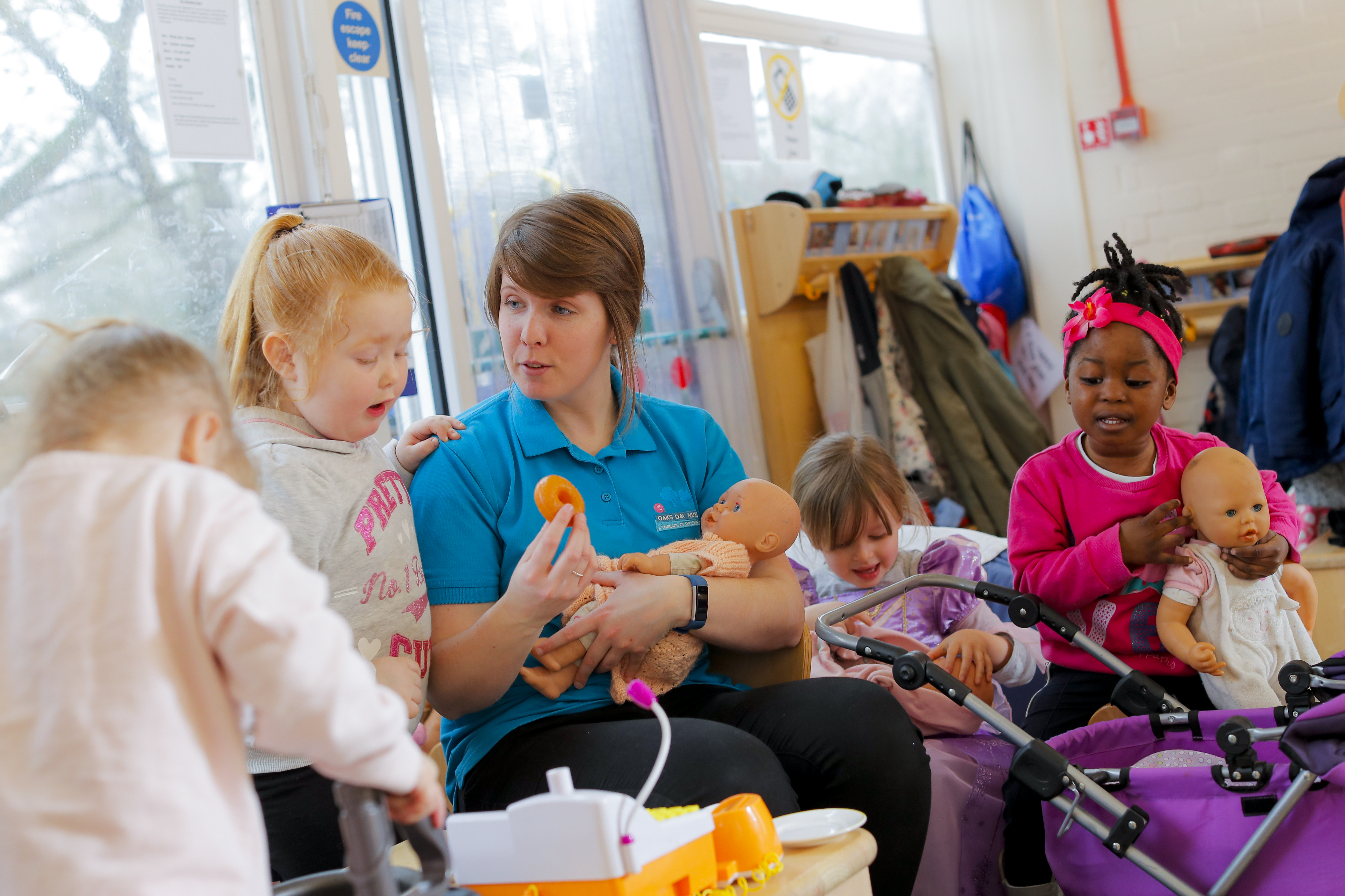 ALT - Nursery teacher holding a dolly and talking to children