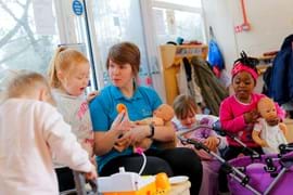 ALT - Nursery teacher holding a dolly and talking to children