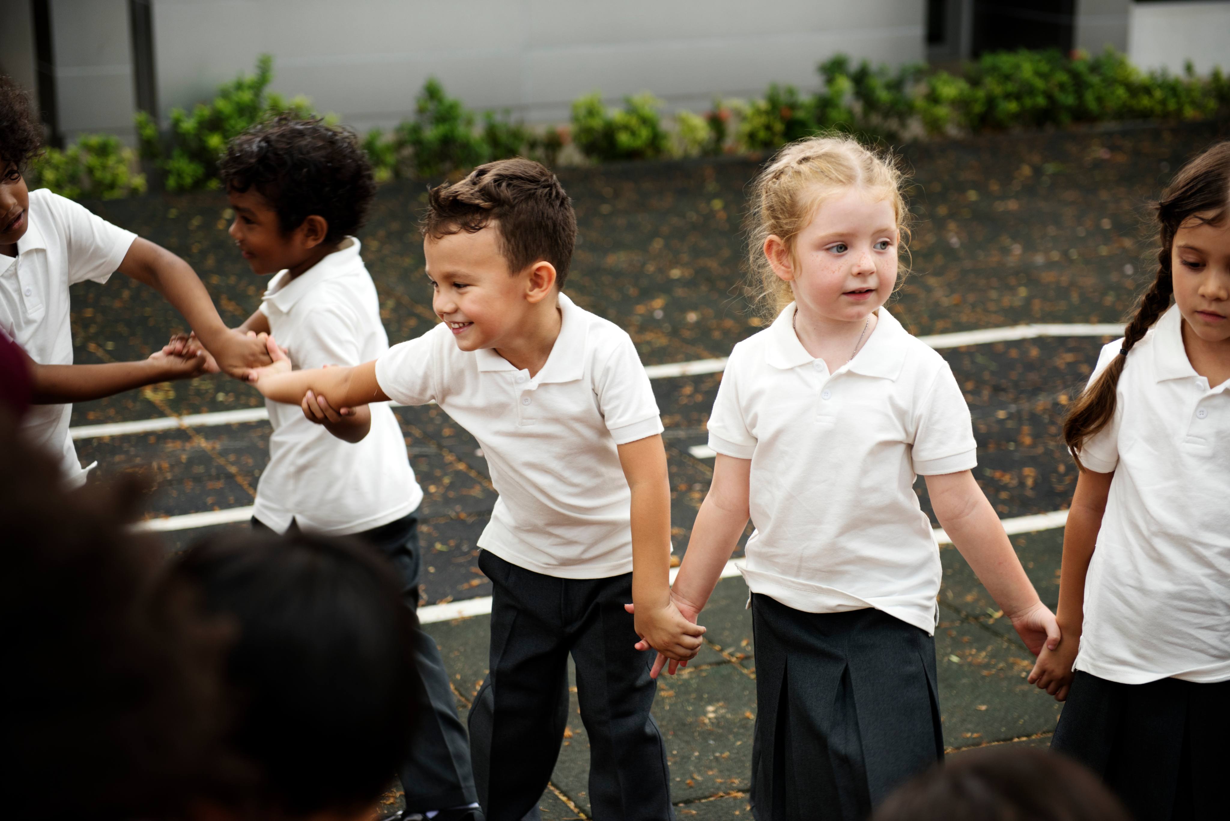 ALT - Children standing in line holding hands in the playground