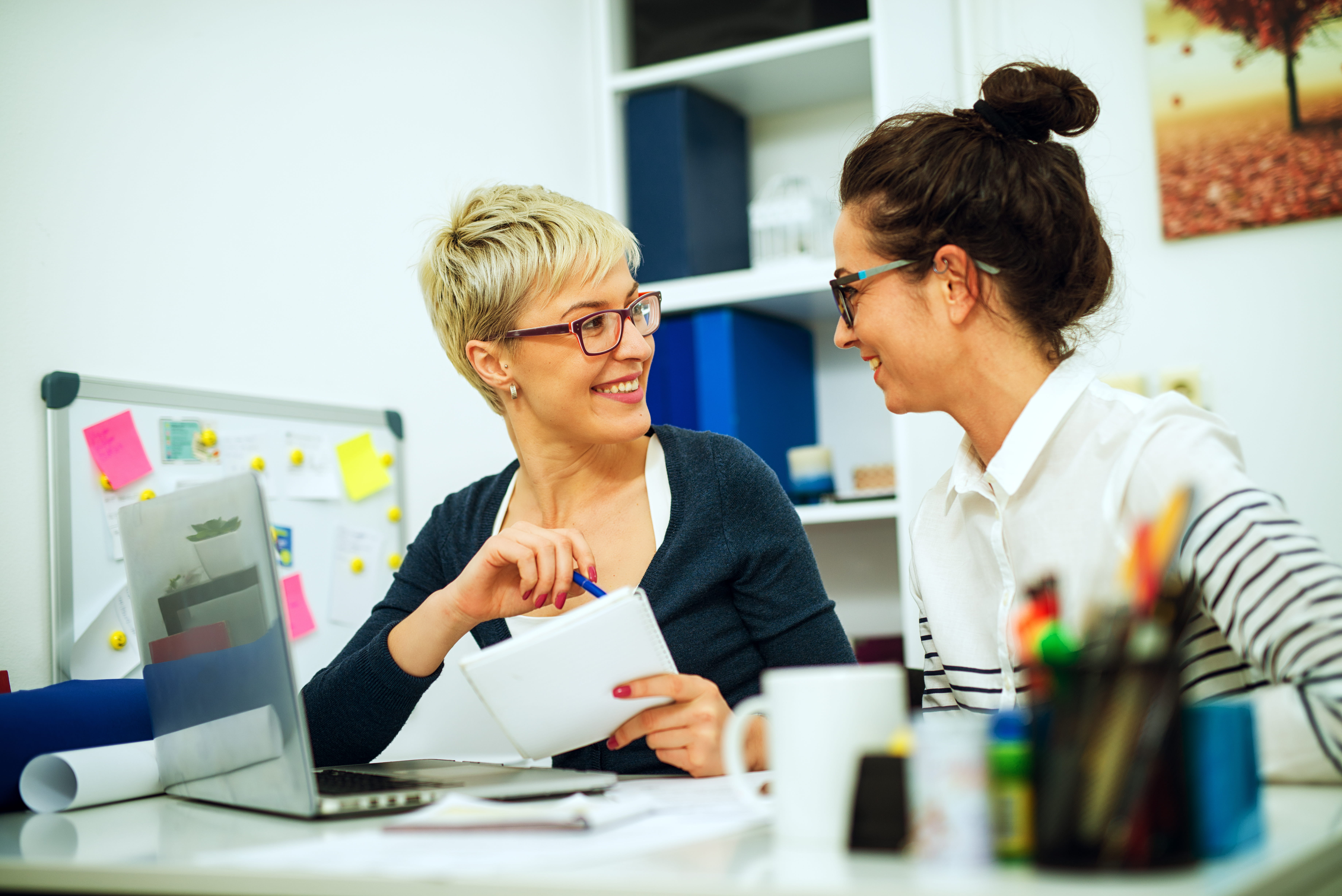 ALT - Two ladies sitting at a desk with a laptop having a conversation