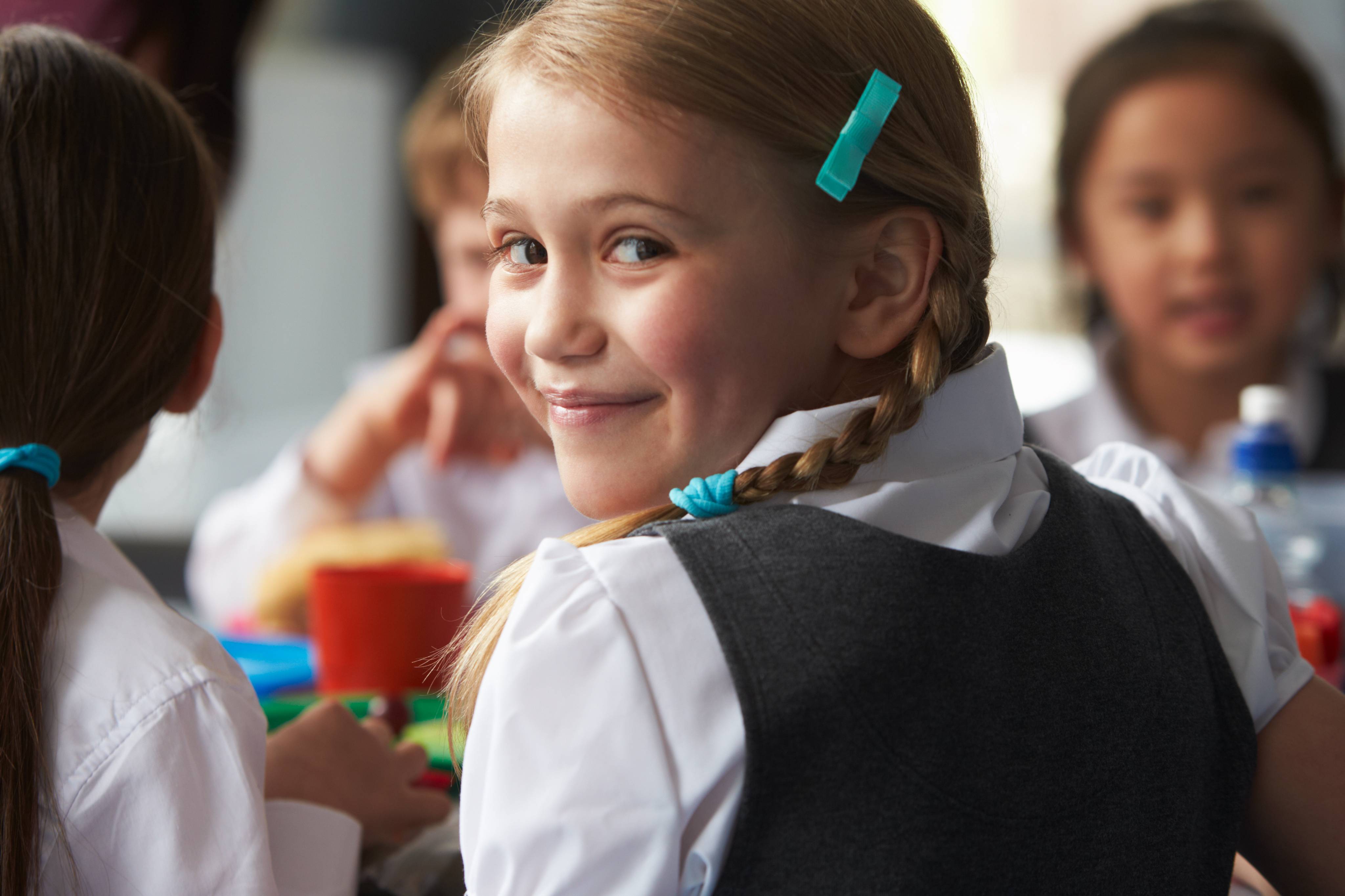 ALT - Child turning to look at the camera smiling with other children sitting in the background 
