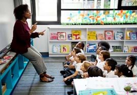 ALT - Teacher talking in front of class using her hands to express herself