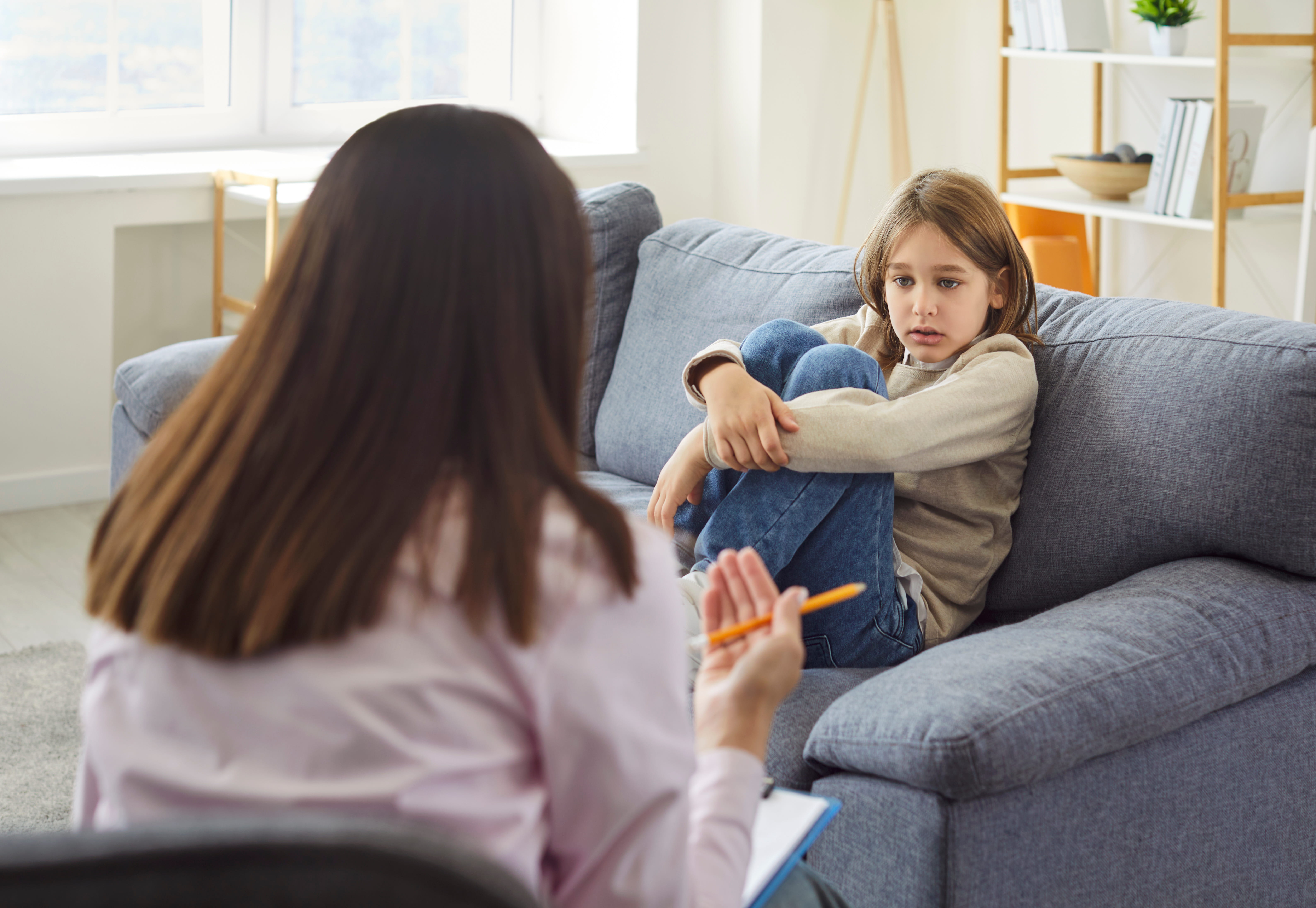 ALT - adult and child sitting opposite each other, child has his legs up on the chair hugging them