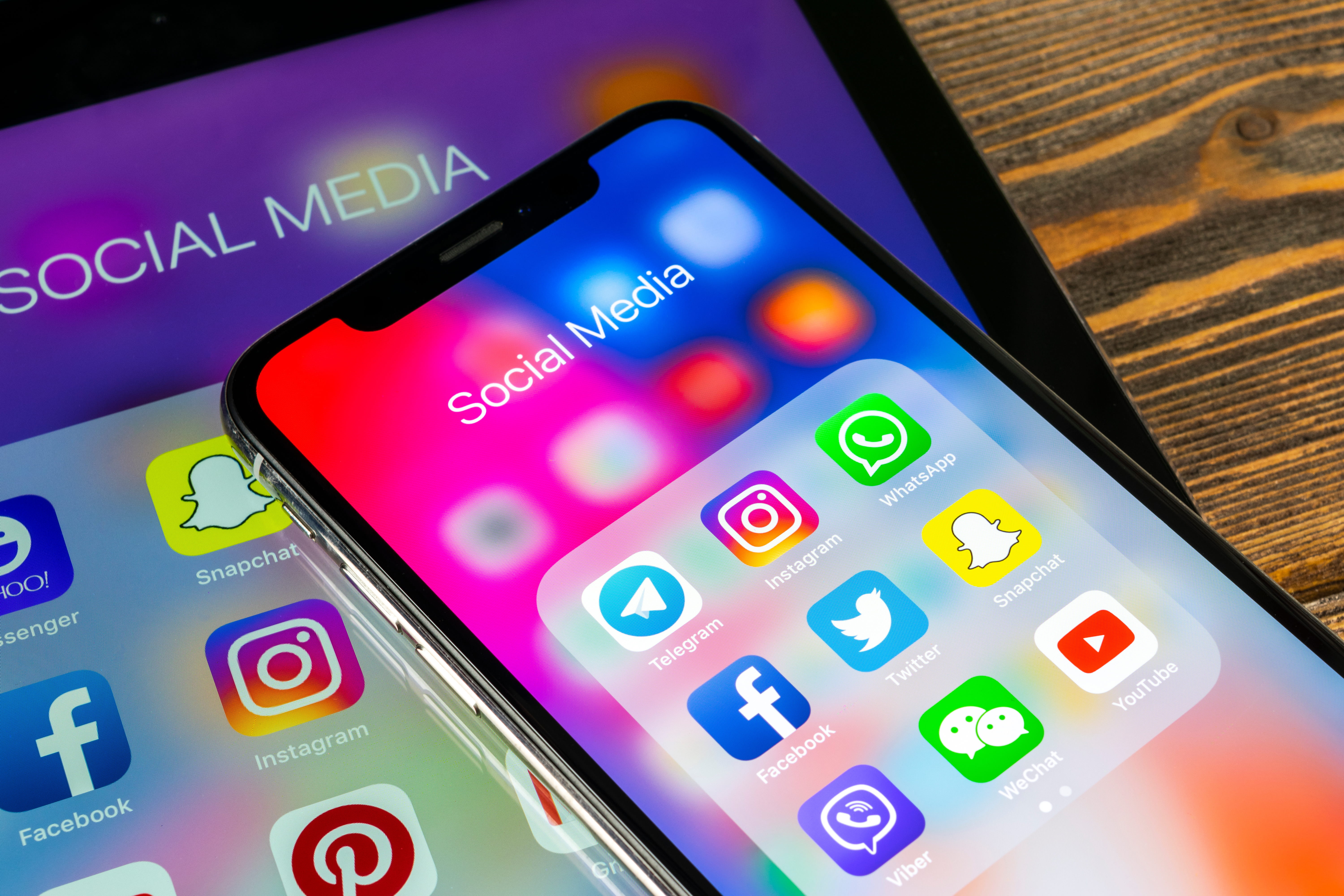 Smartphone displaying social media apps like Instagram, Facebook, and Twitter, set against a tablet with similar icons.