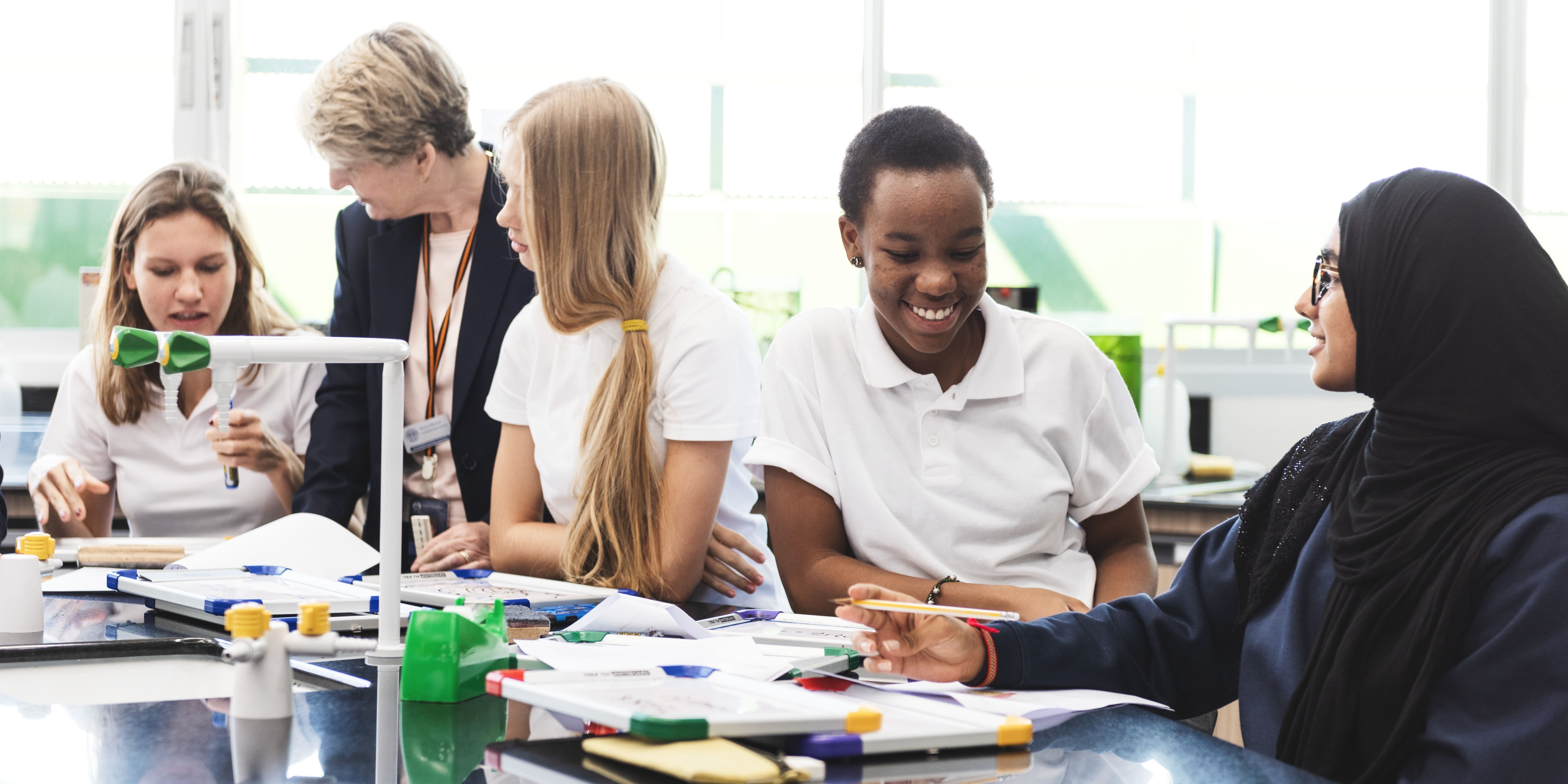 A diverse group of students in a science class, smiling and engaged in discussion